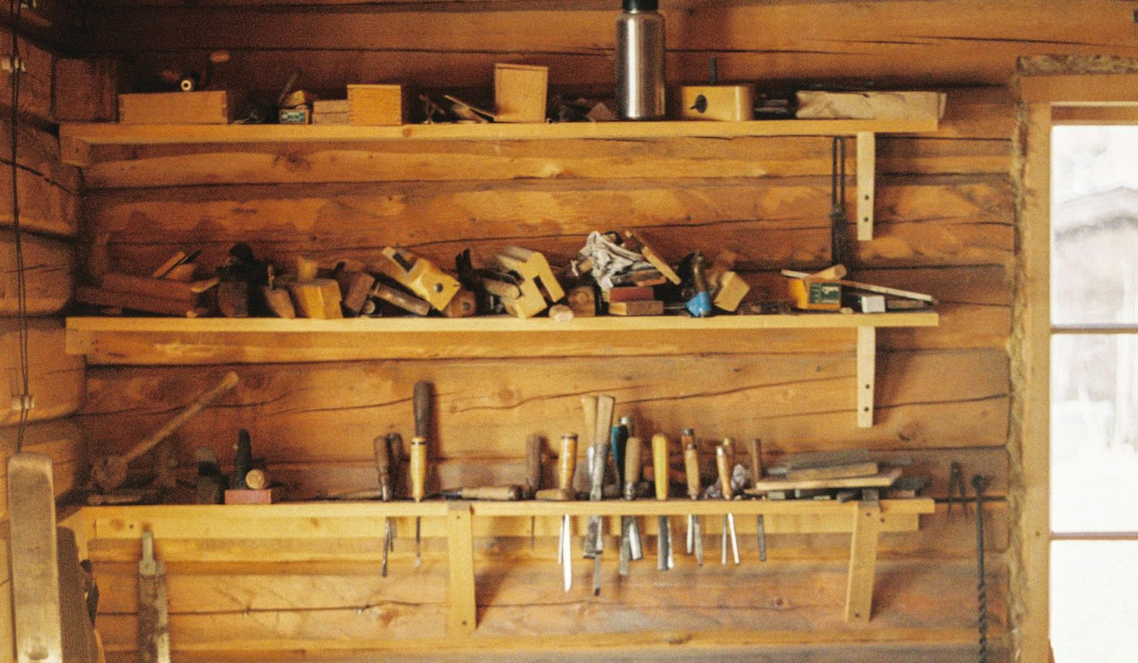 Werkzeugwand mit Hobeln, Stechbeiteln und Sägen in einer holzverkleideten Werkstatt